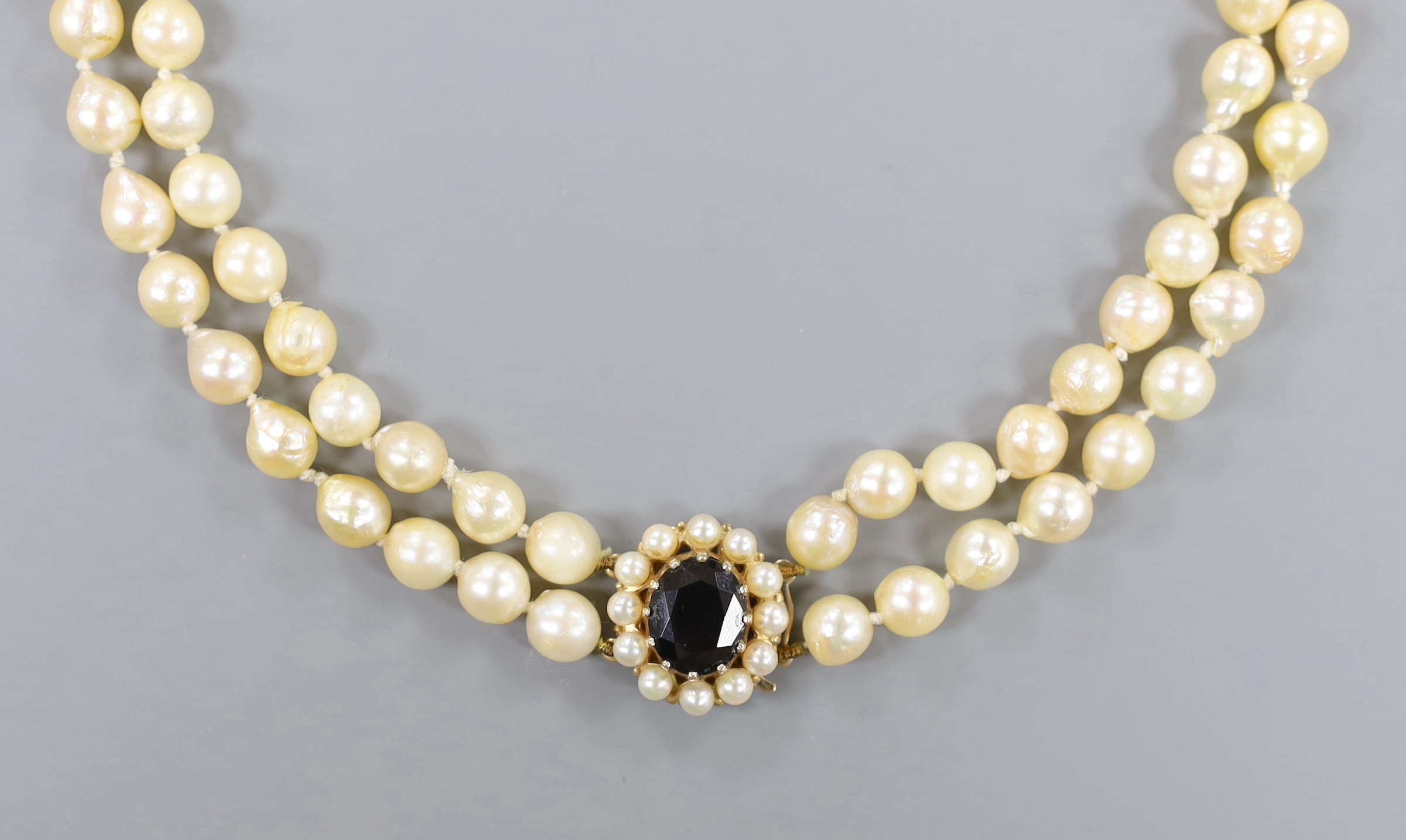 A twin strand cultured pearl necklace with a 9ct gold and garnet set clasp, 39cm.